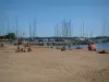 Sainte-Maxime - Plage de sable de la station balnéaire avec des estivants, mer méditerranée et voiliers (bateaux) du port de plaisance
