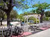 Les Saintes - Terre-de-Haut square decorated with trees and benches, electric bikes in the foreground