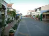 Les Saintes-Maries-de-la-Mer - Street lined with restaurants and with white houses decorated with flowers and plants