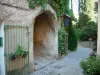 Séguret - Calle pavimentada con un arco y una casa adornada con rosas, plantas y flores