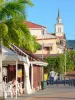 Os Trois-Îlets - Terraço de café, casas da aldeia e torre sineira da igreja de Notre-Dame-de-la-Bonne-Délivrance