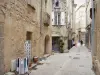 Uzès - Casco antiguo: calle empedrada rodeada de tiendas y casas de piedra