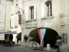 Uzès - Place aux Herbes: arcos (arcos, cubierto), frentes de las casas, tienda y restaurante con terraza