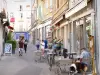 Valence - Calle comercial con tiendas y cafetería con terraza.