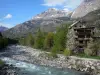 Vallouise - Arbres et maisons au bord de la rivière, montagnes surplombant l'ensemble ; dans le Parc National des Écrins