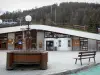 Vars - Vars-la-Claux, estación de esquí (estación de esquí y de verano): plaza con una fuente y un banco de madera, la construcción de viviendas de la oficina de turismo y de los árboles en el fondo